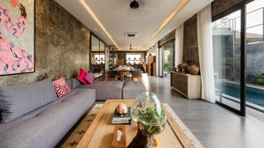 A modern living room with a gray sofa, a coffee table with decorative items, and a large painting on the wall.
