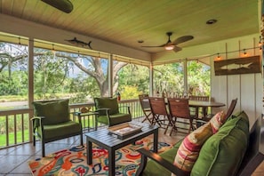 A covered outdoor seating area with a table, chairs, and a sofa.
