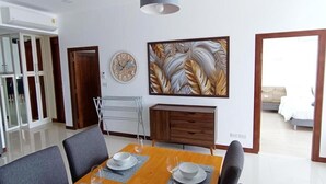 A modern dining area with a wooden table set for six, grey upholstered chairs, and pendant lighting.