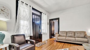 Un salon comprenant un canapé en cuir, un fauteuil en cuir, une table basse en bois et un tapis à motifs.
