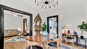 Un coin repas avec une table en bois, quatre chaises, un vase et un ventilateur de plafond.