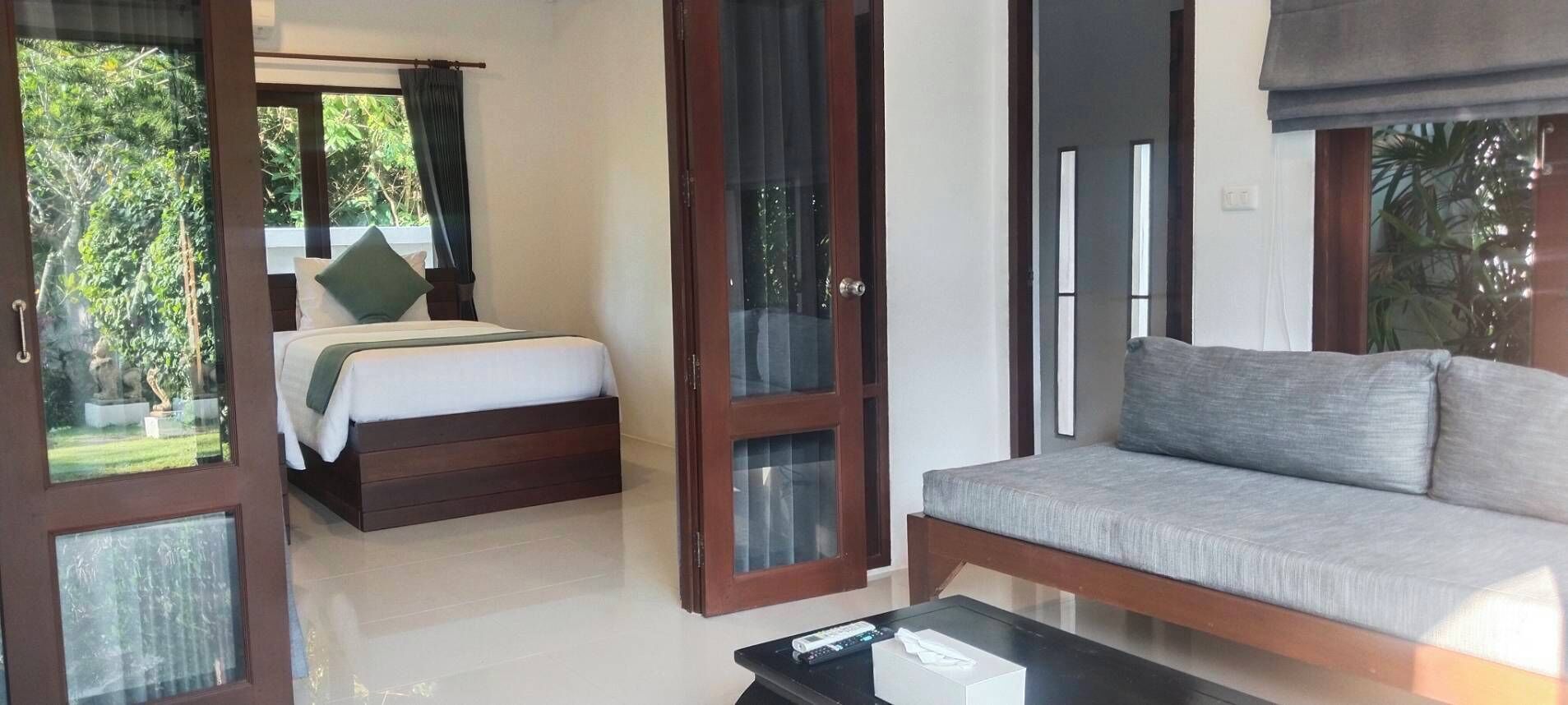 Un dormitorio con cama, sofá y una mesita. Hay puertas de cristal que dan a un balcón.