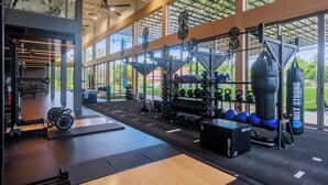 Un gimnasio con equipo de levantamiento de pesas, máquinas de cardio y un saco de boxeo.