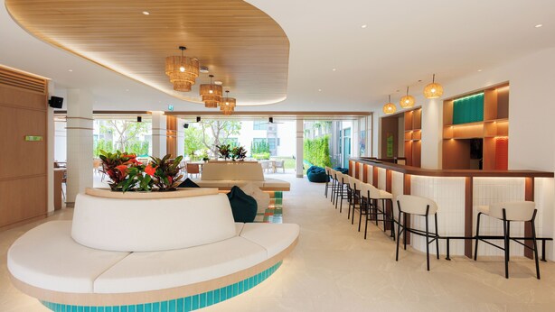 Un moderno vestíbulo con una zona de estar curva, un bar con taburetes y vistas al exterior.