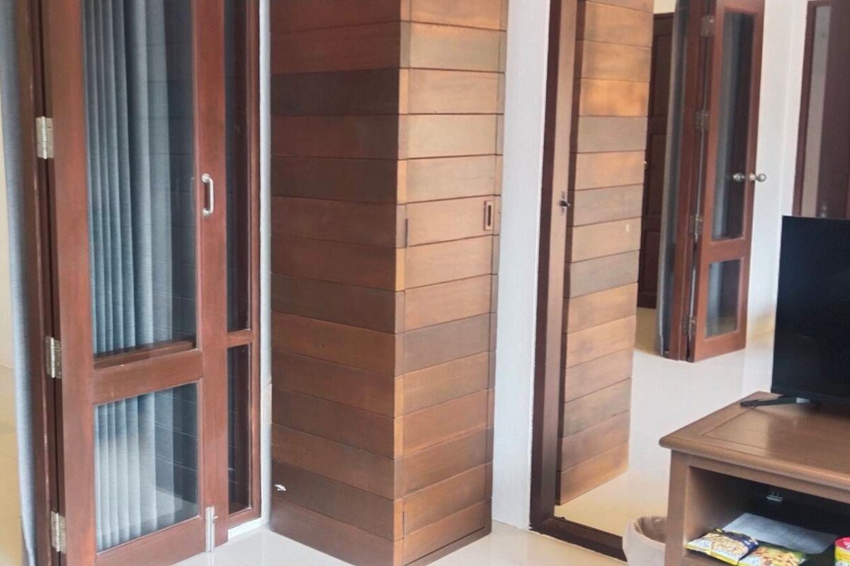 Un dormitorio con cama, un mueble para televisor y una puerta corredera que da a un balcón.