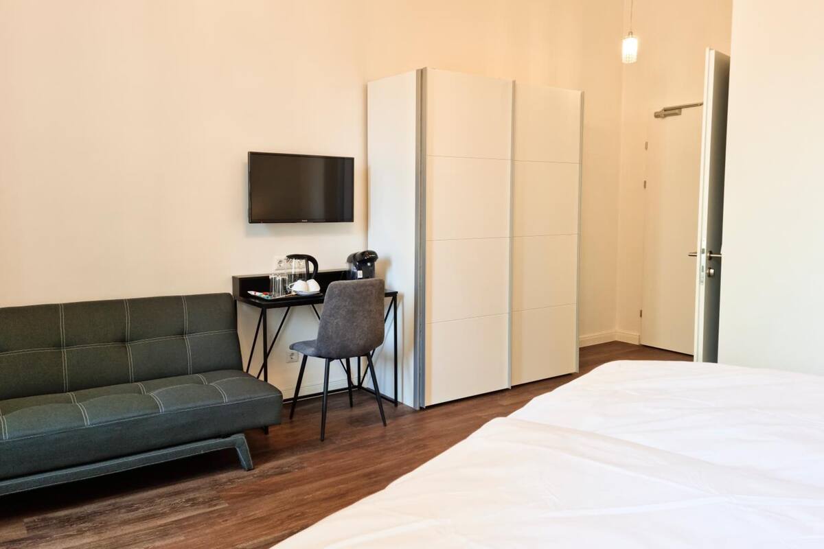 Ein Hotelzimmer mit Bett, einer Couch, einem Schreibtisch mit Fernseher und einem Kleiderschrank.