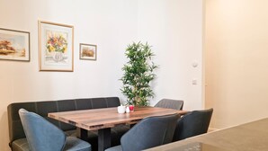 A dining area with a wooden table, four chairs, a bench, and a potted plant.