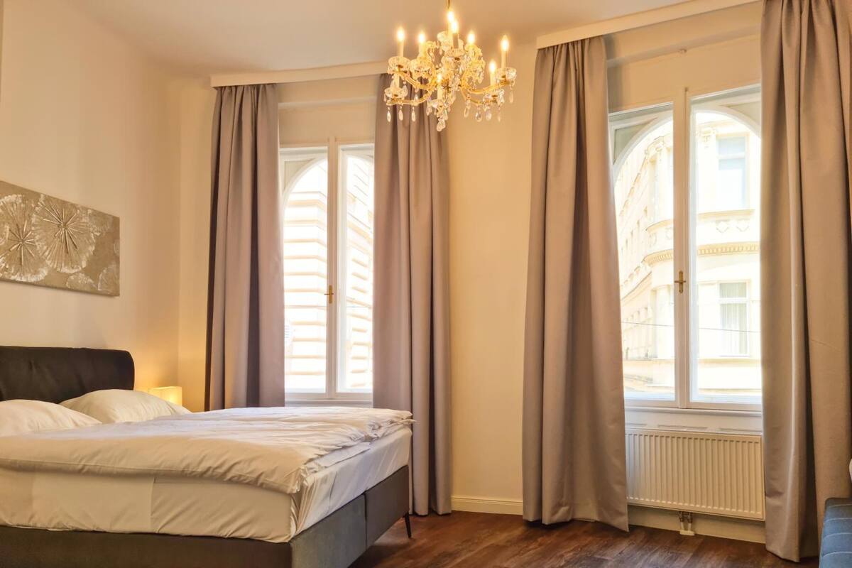 Ein Schlafzimmer mit Bett, einer Kronleuchter und einem fenster mit Vorhängen.