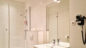 Ein modernes Badezimmer mit Duschkabine aus Glas, einem weißen Waschbecken mit Spiegel und einem an der Wand befestigten Föhn.