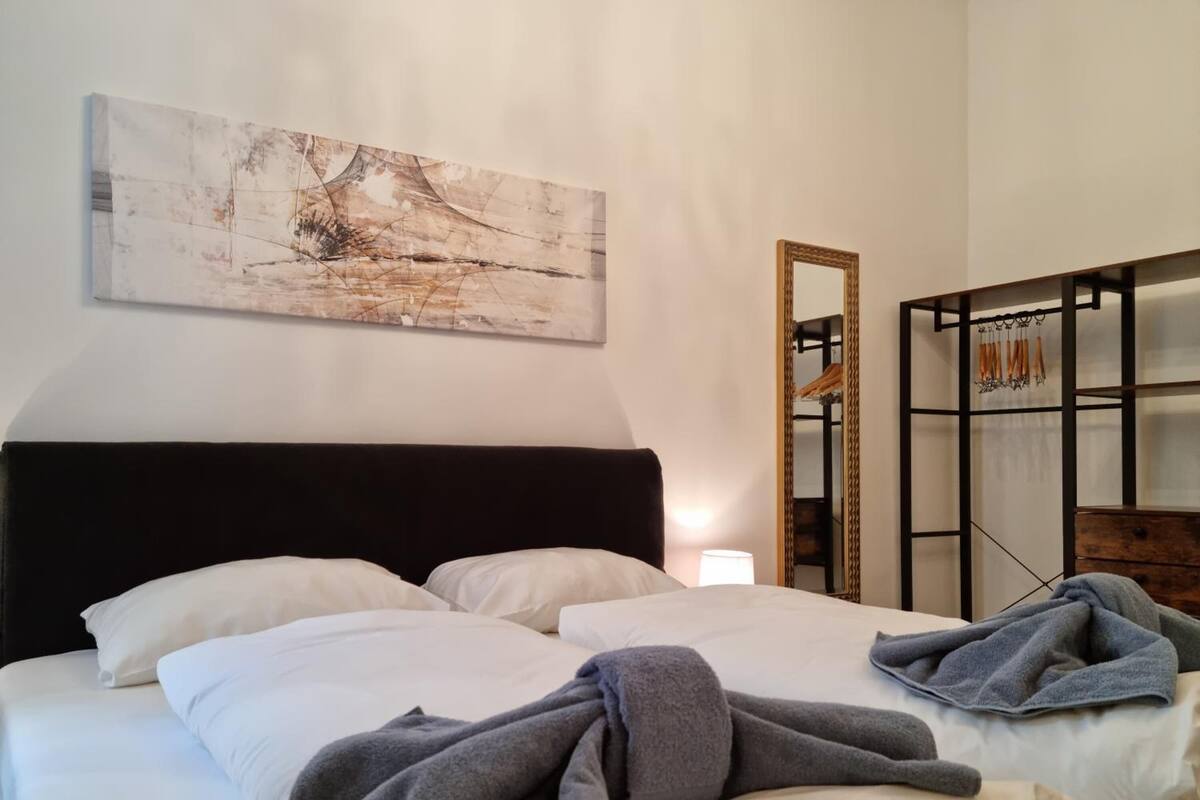 Ein Hotelzimmer mit einem Bett, einem großen abstrakten Gemälde, einem Spiegel und einem Schrank.