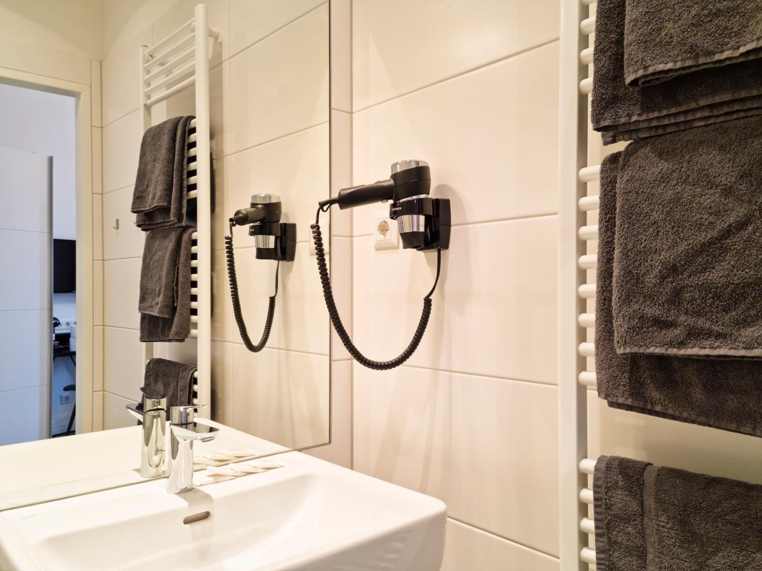 A bathroom with a white sink, a mirror, and towels hanging on a rack.