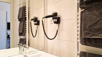 A bathroom with a white sink, a mirror, and towels hanging on a rack.