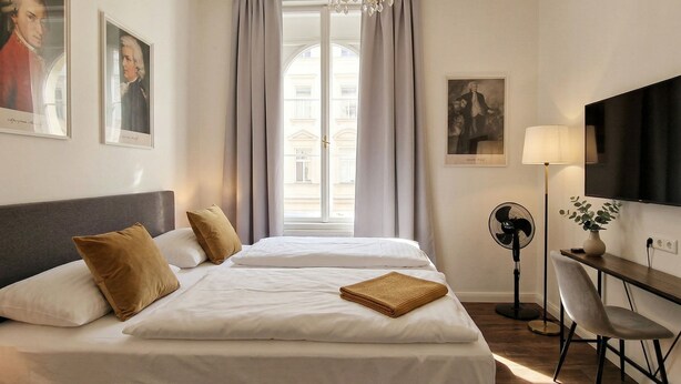 A hotel room with a large bed, a desk with a chair, a TV, and a window with curtains.