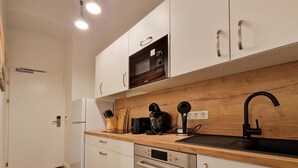 A modern kitchen with white cabinets, a wooden countertop, a built-in microwave, a sink, and a Bosch dishwasher.