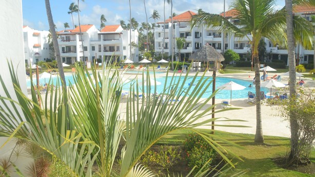 A resort with a swimming pool, palm trees, and a beach area. - Beach apartment stanza mare (Punta Cana)