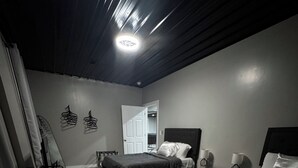 A bedroom with two beds, a wooden floor, and a ceiling light. - BRAND NEW, SPACIOUS, FUN - The Wolves Den on Fraley (Kane)