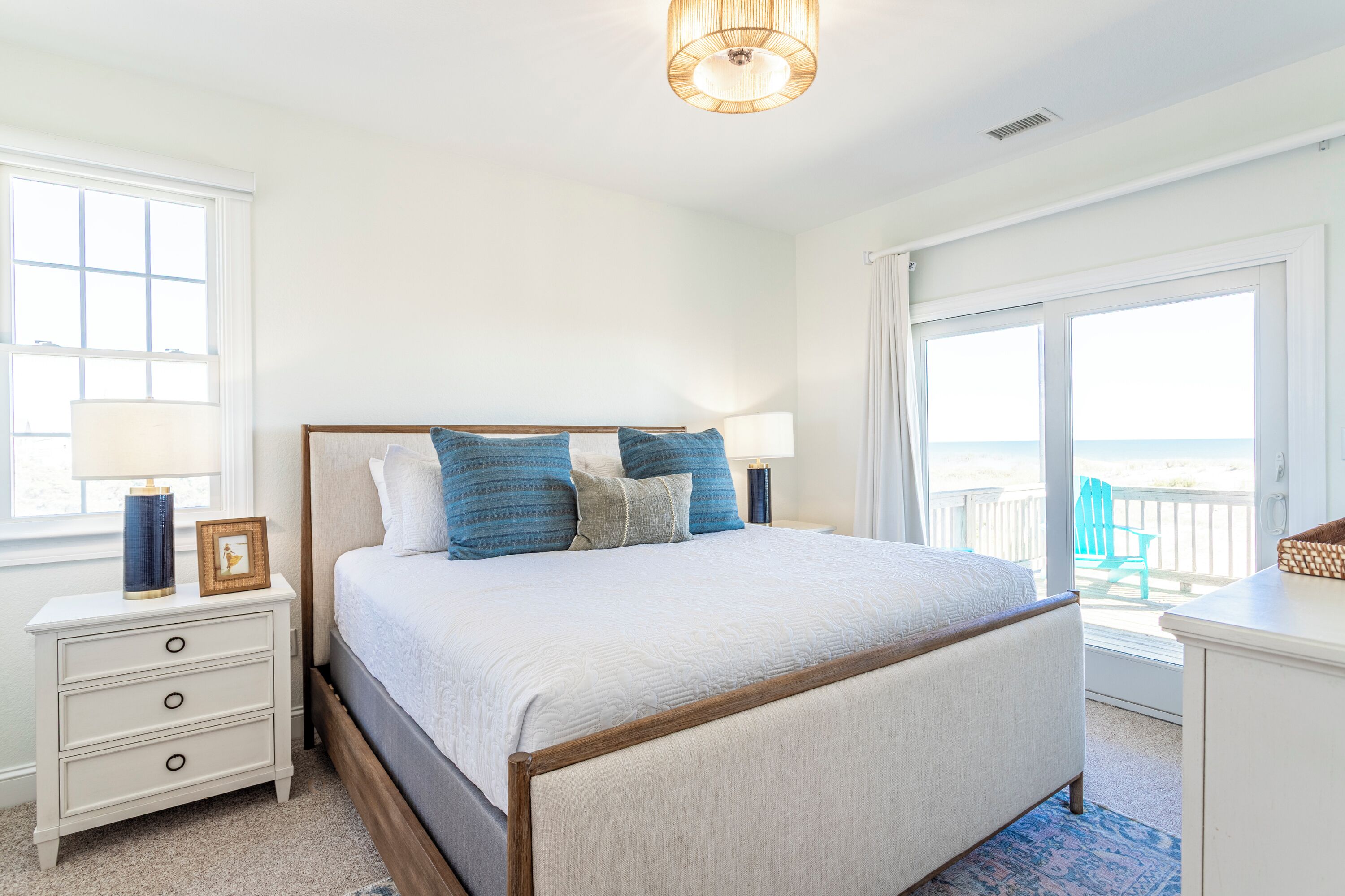 Une chambre avec un grand lit, une table de chevet, une commode et une vue sur l’extérieur grâce à une porte-fenêtre coulissante.