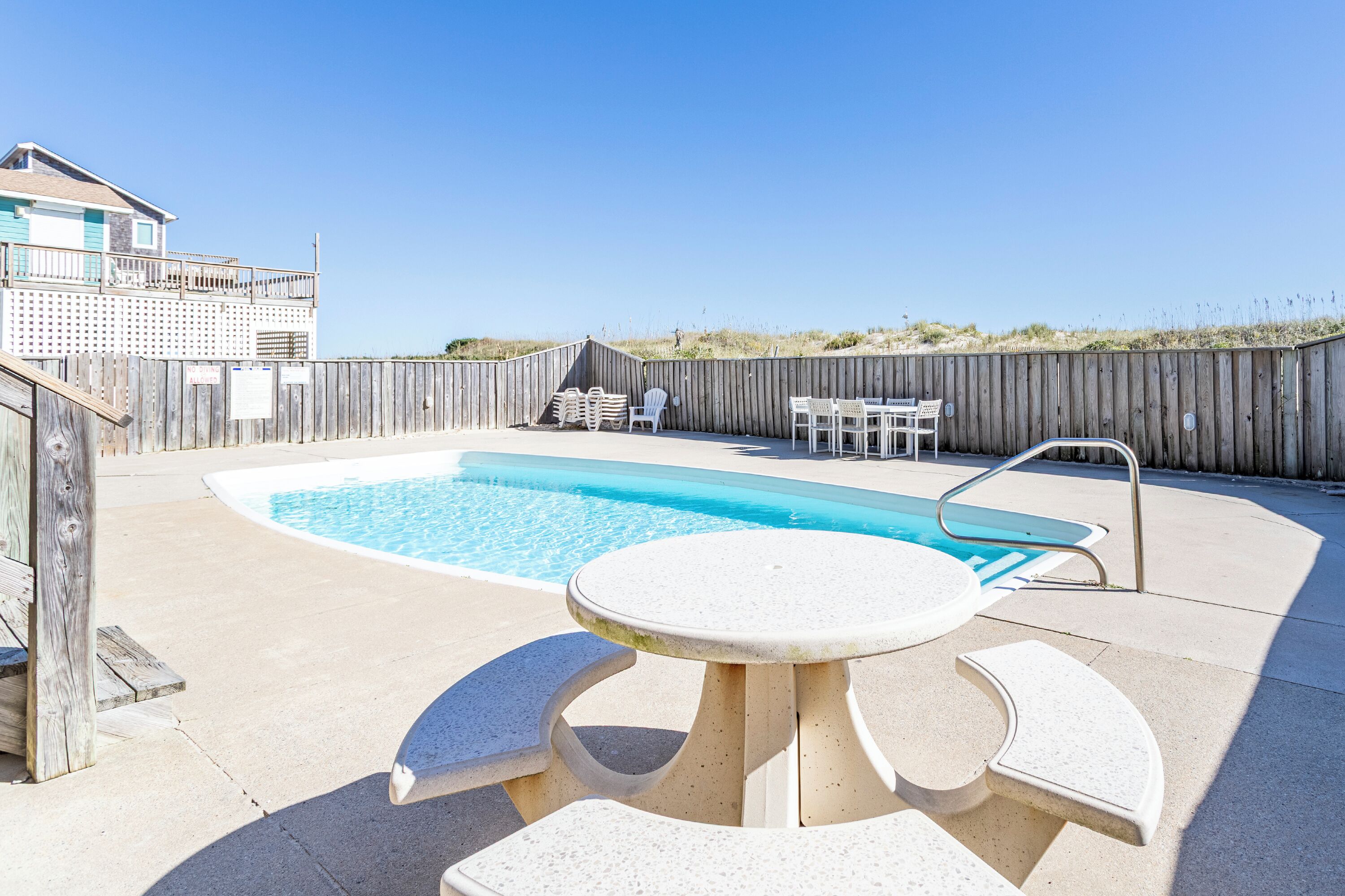 Un jardin avec une piscine, une clôture en bois et du mobilier d’extérieur.