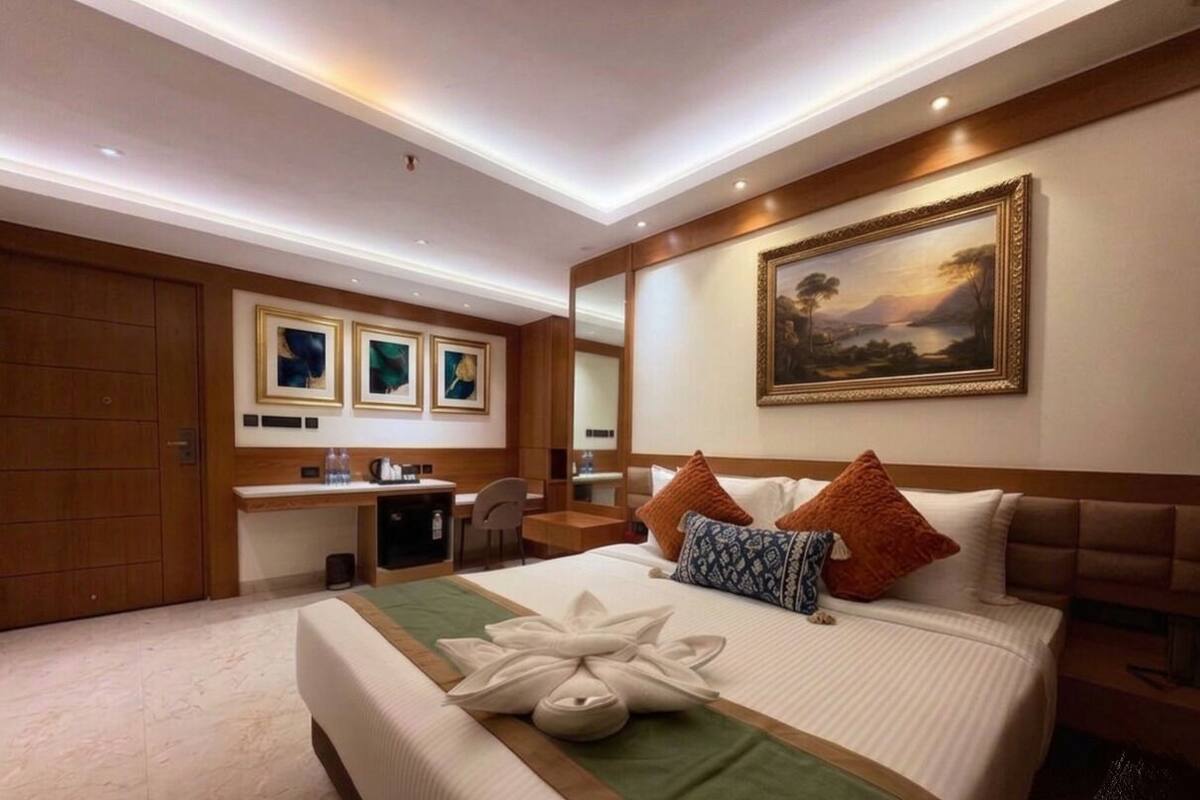 A hotel room with a large bed, a desk, and a painting on the wall.