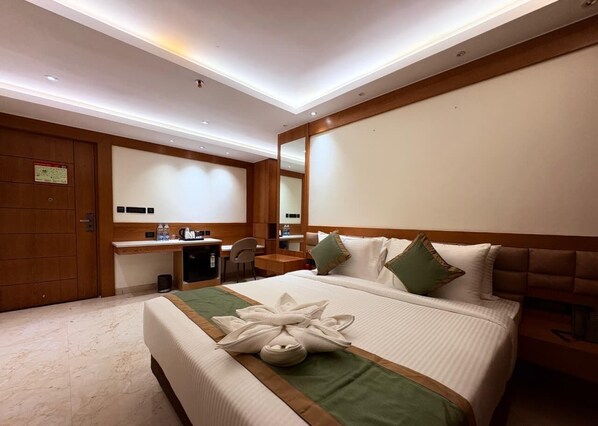 A hotel room with a large bed, a desk, and a mirror.