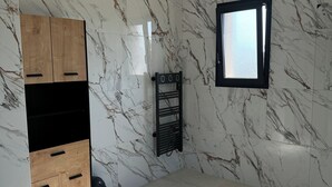 Ein Zimmer mit Wänden im Marmor-Muster, einem Holzschrank, einem schwarzen Heizkörper und einem Fenster mit Blick.