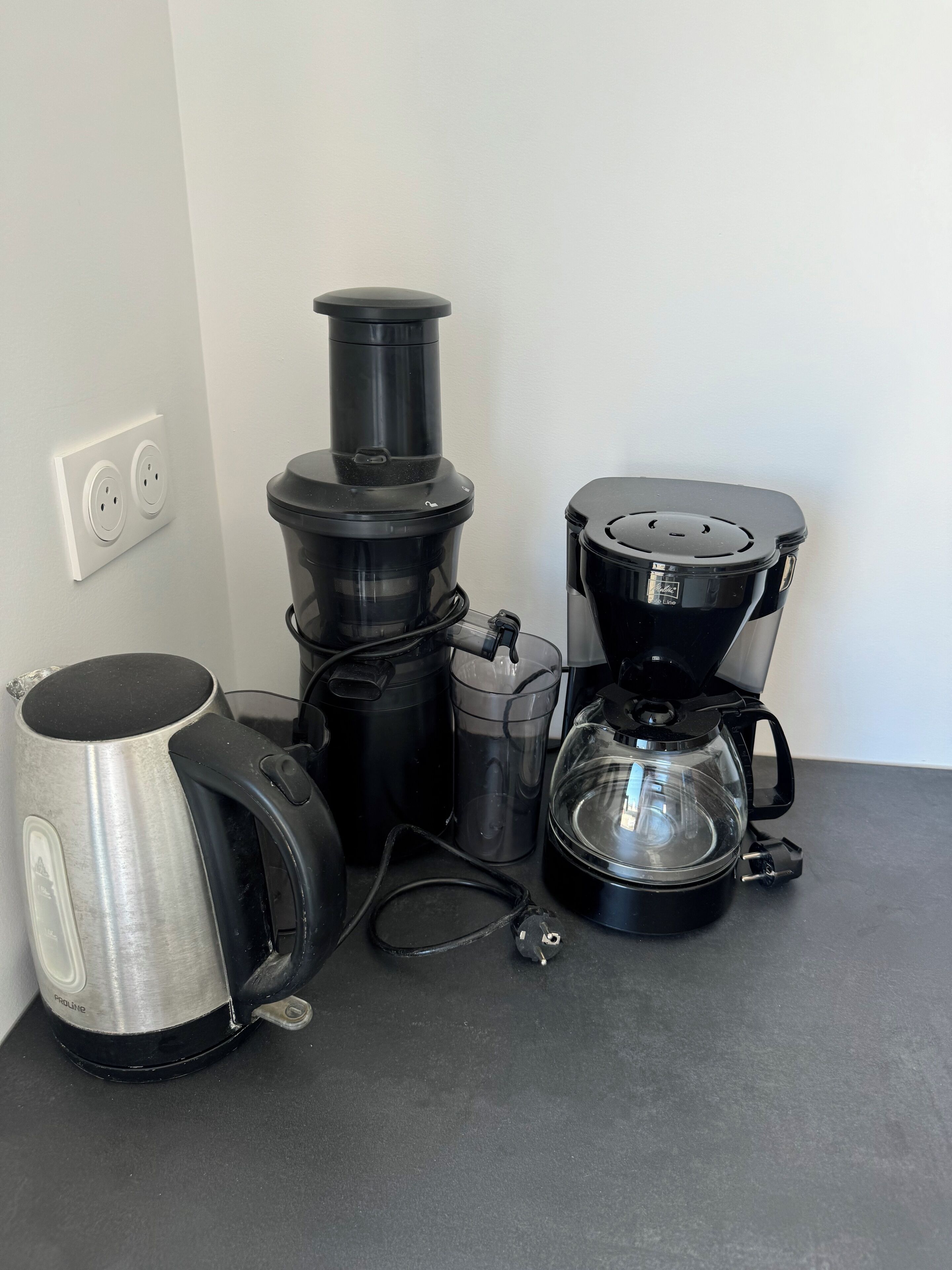 Eine Küchenarbeitsplatte mit Kaffeemaschine, Wasserkocher und Mixer.