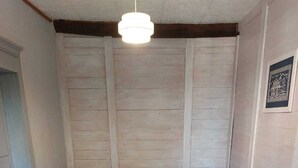Een slaapkamer met een bed, houten wanden, een plafondlamp en twee nachtkastjes met lampen.