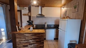 Een kleine keuken met een houten keukeneiland, een vaatwasser en een koelkast.