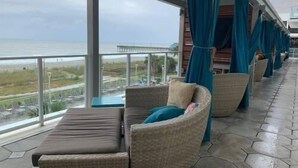 A balcony with wicker furniture and a view of the beach. - Ocean Enclave July 4th weekend. Beachfront hotel. Partial Ocean View 1 bedroom. (Myrtle Beach)