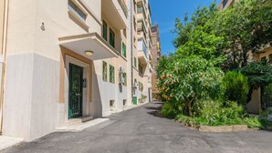 A narrow street lined with multi-story buildings, each with balconies and green shutters. - B&B Loggia Garbatella (Rome)