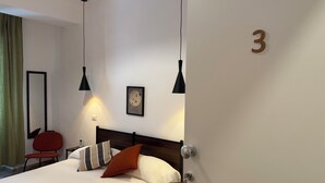 A hotel room with a bed, a chair, a bedside table, a wall clock, and a door marked with the number 3. - B&B Loggia Garbatella (Rome)