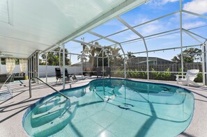 A covered swimming pool with a glass enclosure, surrounded by lounge chairs and a patio area. - 5-Bedroom Sarasota Retreat with Heated Pool mins to Siesta Beach/NO CLEANING FEE (Sarasota)