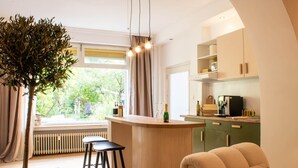 A modern kitchen with a bar area, wooden stools, and a view of greenery outside. - Documenta - With a terrace and a view of the countryside (Kassel)