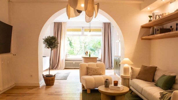 A modern living room with a sofa, armchair, and coffee table, a television, and a bookshelf. - Documenta - With a terrace and a view of the countryside (Kassel)