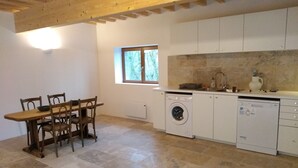 A kitchen with a wooden table and chairs, a washing machine, and a dishwasher. - Large, renovated country house. Children and pets welcome! (Chaumard)