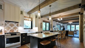 Una cocina moderna con una isla grande, taburetes de madera y luces colgantes.