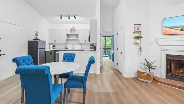 Una cocina moderna con armarios blancos, una isla central y un comedor con sillas azules.