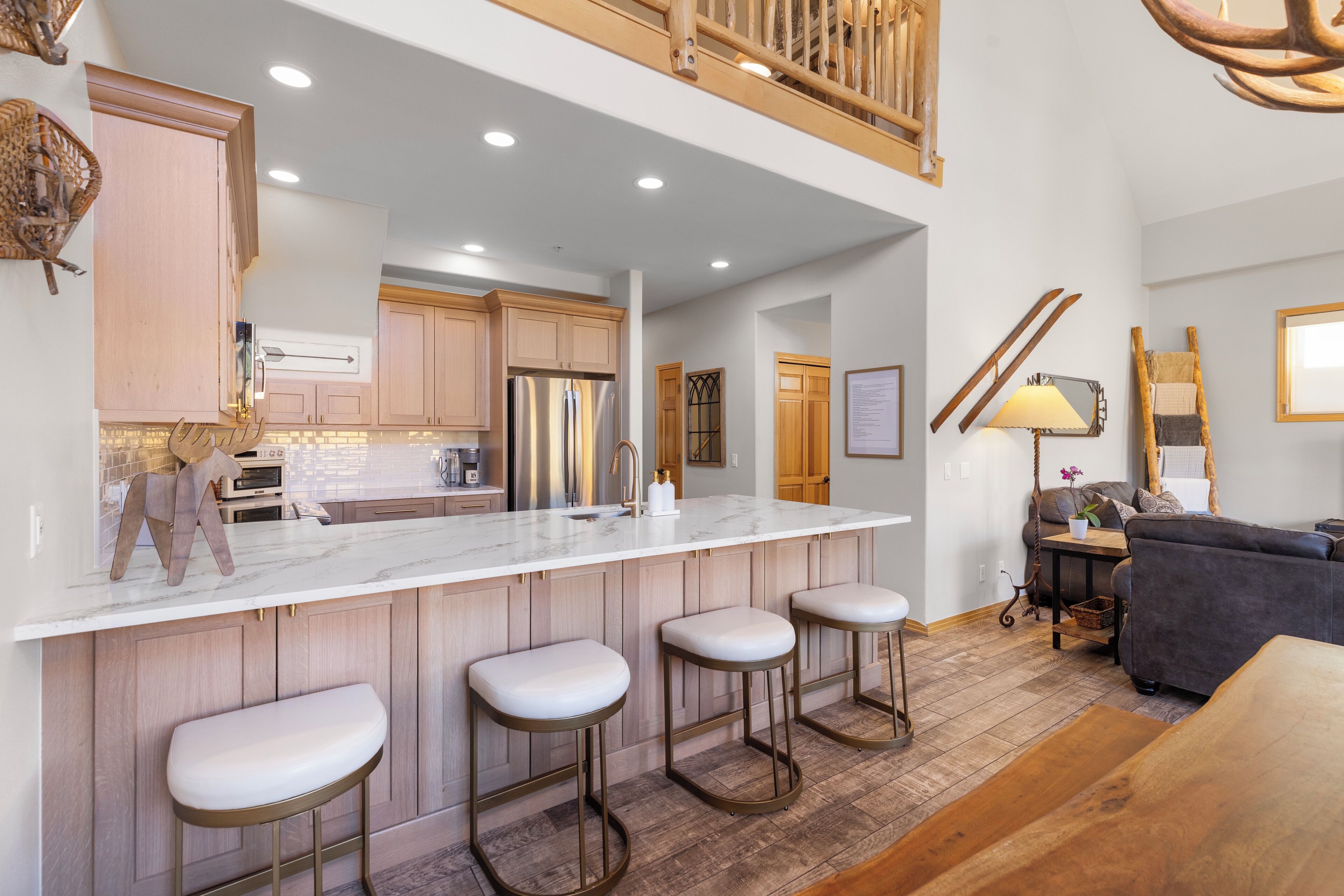 A modern kitchen with a marble countertop, wooden cabinets, and a built-in island with bar stools.