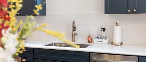 A modern kitchen with dark cabinets, a stainless steel sink, and a dishwasher.