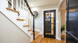 Una escalera con barandillas de madera y una puerta negra con paneles de vidrio.