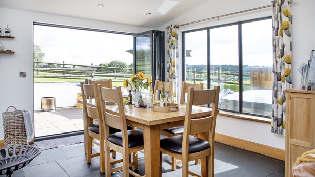 Un comedor con una mesa grande, sillas de madera y vistas a través de un ventanal.