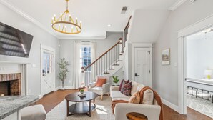 Un salon spacieux avec une cheminée, un escalier et un coin repas.