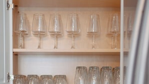 Une cuisine avec un grille-pain sur le plan de travail, une plante en pot et des étagères remplies de verres à vin.