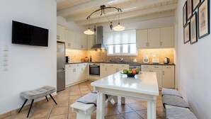 Una cocina moderna con armarios blancos, una isla central y una zona de estar con bancos.