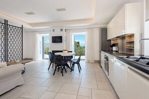 A modern kitchen with a dining area, large windows, and a flat-screen TV. - Thea Estate (Kassopei)