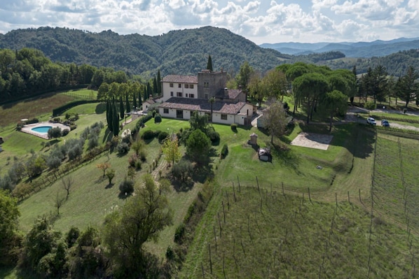 Un vaste domaine comprenant un bâtiment principal, une piscine et de vastes champs verdoyants.