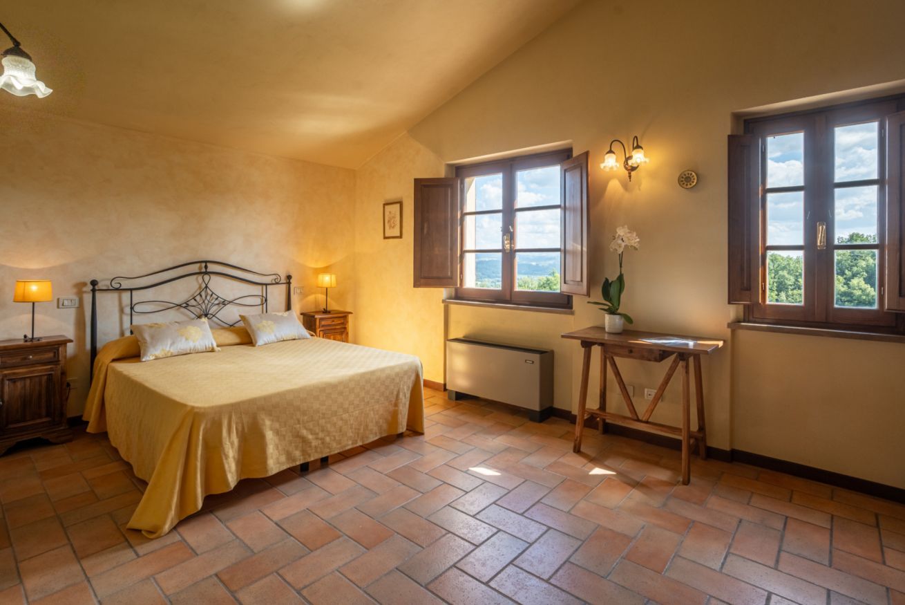 A bedroom with a bed, a desk, a window, and a radiator.