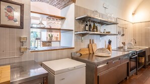 Una cucina moderna con frigorifero integrato, lavello e piano cottura. Sopra il bancone, mensole con stoviglie e bottiglie.