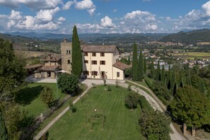 A large, historic building with a well-maintained lawn and a stone tower.