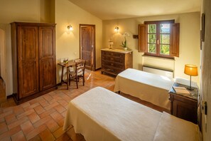 Une chambre avec deux lits, une armoire en bois, un bureau avec une chaise, une commode et une fenêtre donnant sur un beau paysage.